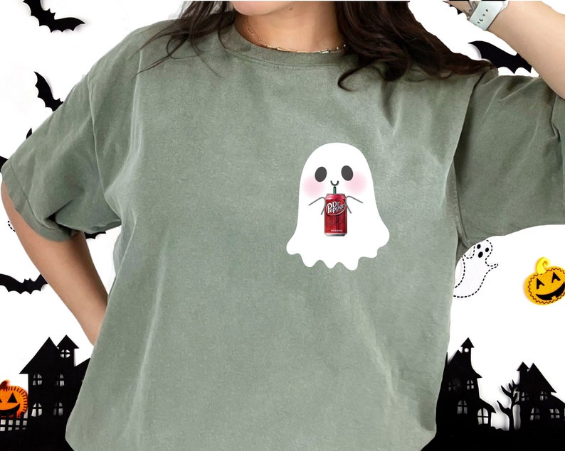 May include: A green t-shirt with a white ghost design holding a red can of Dr Pepper.