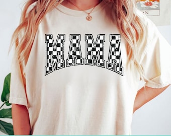 May include: A white t-shirt with the word "MAMA" printed in black and white checkered letters.