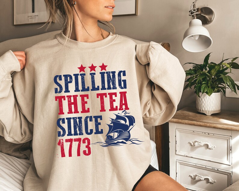 May include: A beige sweatshirt with a blue and red graphic print that says "Spilling the Tea Since 1773" with a ship illustration.