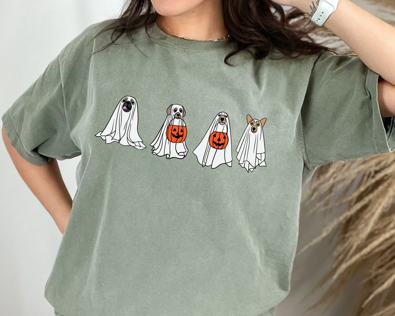 May include: A green t-shirt with a graphic of four dogs dressed as ghosts holding pumpkins for trick or treating.