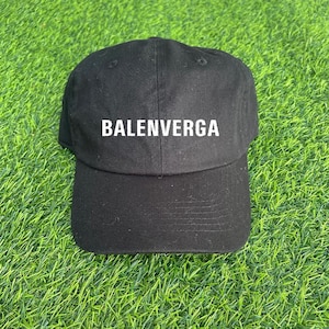 Puede incluir: Gorra de béisbol negra con el texto blanco "BALENVERGA" en la parte delantera. La gorra está hecha de una tela resistente y tiene una visera curva. El sombrero está sobre hierba verde.