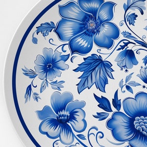 Puede incluir: Un plato de cerámica blanco con un diseño floral azul y blanco. El diseño presenta flores y hojas estilizadas en un patrón tradicional.
