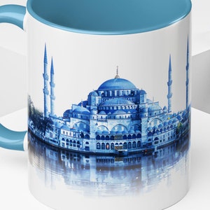 May include: A white ceramic mug with a blue rim and handle. The mug features a colorful image of the Hagia Sophia mosque in Istanbul, Turkey.