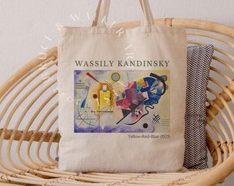Puede incluir: Una bolsa de lona blanca con una pintura abstracta colorida de Wassily Kandinsky. La pintura se titula "Amarillo-Rojo-Azul (1925)".