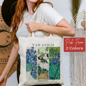 May include: A white tote bag with a print of a Van Gogh painting featuring irises and roses. The text "Van Gogh" and "Irises & Roses" are printed on the bag. The bag is being held by a person.