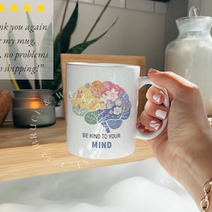 Pode incluir: Caneca de cer&acirc;mica branca com um design de c&eacute;rebro colorido e o texto "Seja gentil com sua mente".
