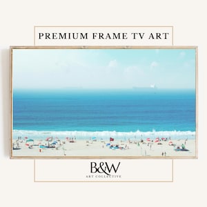 Puede incluir: Una fotografía enmarcada de una escena de playa con un océano azul, arena blanca y gente disfrutando del sol. La foto está enmarcada en un marco de madera clara y tiene el texto "B&W ART COLLECTIVE" en la parte inferior.