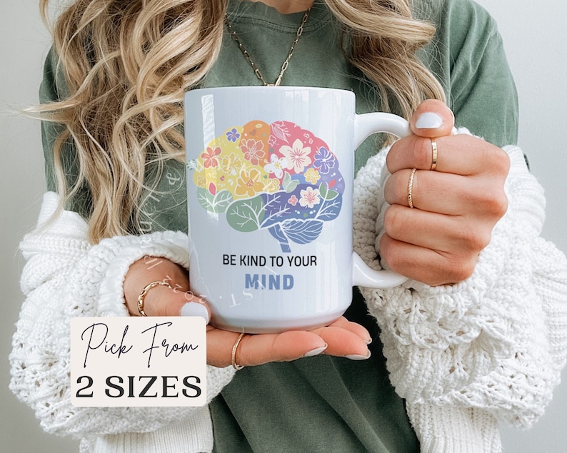 Pode incluir: Caneca de cer&acirc;mica branca com um design de c&eacute;rebro colorido e o texto "Seja gentil com sua mente".