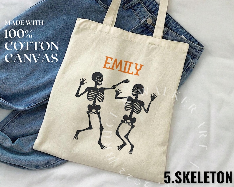 May include: A white canvas tote bag with black skeleton figures and the text "Emily" printed in orange. The bag is made with 100% cotton canvas.