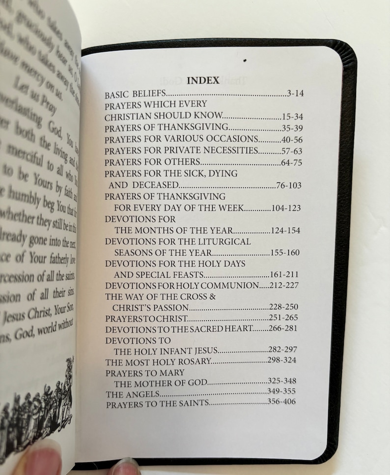 May include: Open book with a black cover, displaying an index of prayers and devotions. The index includes topics such as basic beliefs, prayers for various occasions, and prayers to the saints. The pages are white with black text.