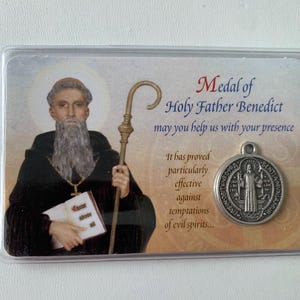 May include: A card with a picture of Saint Benedict and a medal with his image. The card reads "Medal of Holy Father Benedict may you help us with your presence. It has proved particularly effective against temptations of evil spirits..."