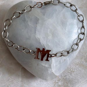 May include: A silver chain bracelet with a silver charm that says "MM".