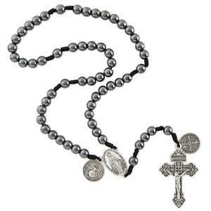 May include: A black hematite rosary with a silver crucifix and three silver medallions. The medallions feature images of the Virgin Mary, Saint Michael the Archangel, and Saint Benedict.
