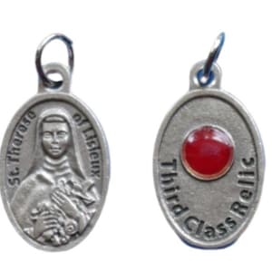 May include: Silver oval pendant with a red glass relic and the text "Third Class Relic". The other side of the pendant features a depiction of St. Therese of Lisieux.