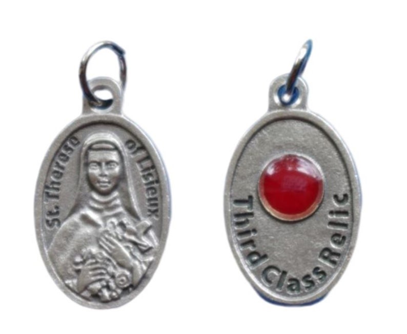 May include: Silver oval pendant with a red glass relic and the text "Third Class Relic". The other side of the pendant features a depiction of St. Therese of Lisieux.
