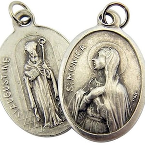 May include: Two silver oval-shaped medallions with images of Saint Augustine and Saint Monica. The medallions have a loop at the top for hanging.