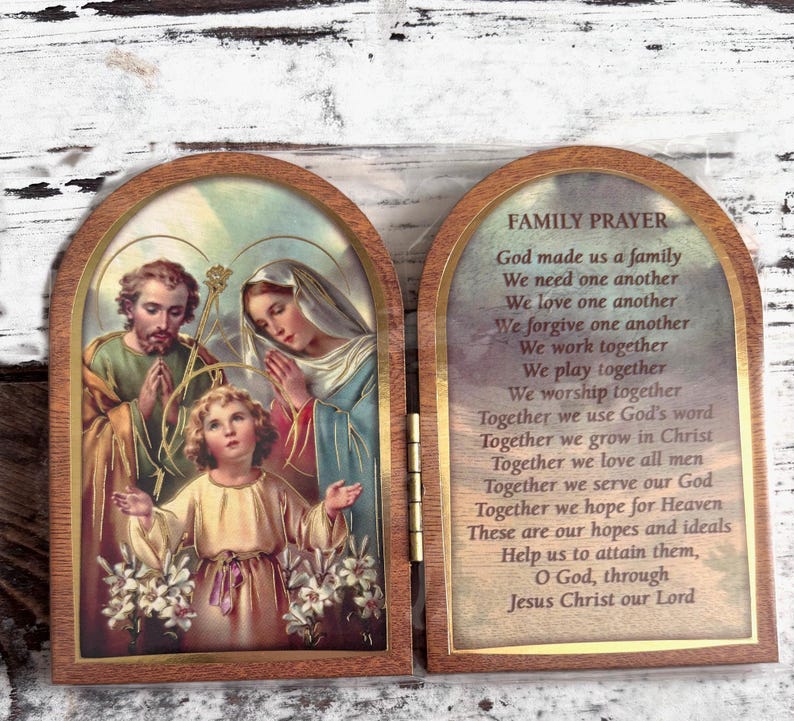 Puede incluir: Una caja de oraci&oacute;n de madera con un panel frontal con bisagras. El panel frontal presenta una pintura de la Sagrada Familia, con Jos&eacute;, Mar&iacute;a y Jes&uacute;s. El panel posterior tiene una oraci&oacute;n para las familias, que dice: "Dios nos hizo una familia. Nos necesitamos unos a otros. Nos amamos unos a otros. Nos perdonamos unos a otros. Trabajamos juntos. Jugamos juntos. Adoramos juntos. Juntos usamos la palabra de Dios. Juntos crecemos en Cristo. Juntos amamos a todos los hombres. Juntos servimos a nuestro Dios. Juntos esperamos el Cielo. Estas son nuestras esperanzas e ideales. Ay&uacute;danos a alcanzarlas, oh Dios, a trav&eacute;s de Jesucristo nuestro Se&ntilde;or."