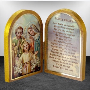 Puede incluir: Una caja de oraci&oacute;n con bisagras de madera con una imagen de la Sagrada Familia en la parte delantera y una oraci&oacute;n para las familias en el interior. La oraci&oacute;n dice: "Dios nos hizo una familia, Nos necesitamos unos a otros, Nos amamos unos a otros, Nos perdonamos unos a otros, Trabajamos juntos, Jugamos juntos, Adoramos juntos, Juntos usamos la palabra de Dios, Juntos crecemos en Cristo, Juntos amamos a todos los hombres, Juntos servimos a nuestro Dios, Juntos esperamos el Cielo, Estas son nuestras esperanzas e ideales, Ay&uacute;danos a alcanzarlas, Oh Dios, a trav&eacute;s de Jesucristo nuestro Se&ntilde;or."