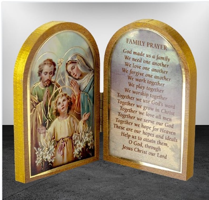Puede incluir: Una caja de oraci&oacute;n con bisagras de madera con una imagen de la Sagrada Familia en la parte delantera y una oraci&oacute;n para las familias en el interior. La oraci&oacute;n dice: "Dios nos hizo una familia, Nos necesitamos unos a otros, Nos amamos unos a otros, Nos perdonamos unos a otros, Trabajamos juntos, Jugamos juntos, Adoramos juntos, Juntos usamos la palabra de Dios, Juntos crecemos en Cristo, Juntos amamos a todos los hombres, Juntos servimos a nuestro Dios, Juntos esperamos el Cielo, Estas son nuestras esperanzas e ideales, Ay&uacute;danos a alcanzarlas, Oh Dios, a trav&eacute;s de Jesucristo nuestro Se&ntilde;or."