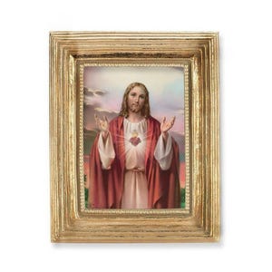 May include: A framed religious print featuring a portrait of Jesus with outstretched arms. The image shows Jesus wearing a white robe and a red cloak, with a heart symbol on his chest. The frame is gold-colored.
