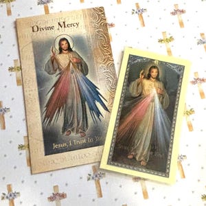 May include: Two religious cards featuring an illustration of Jesus with rays of light emanating from his chest. The larger card reads "Divine Mercy" at the top and "Jesus, I Trust in You" at the bottom. The smaller card has the same image and text.