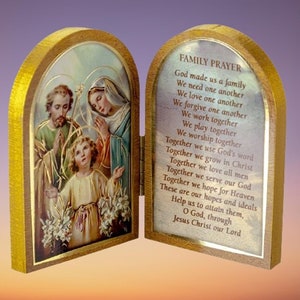 Puede incluir: Una caja de oraci&oacute;n de madera con un frente con bisagras. El frente presenta una imagen colorida de la Sagrada Familia, con Jes&uacute;s, Mar&iacute;a y Jos&eacute;. La parte posterior de la caja tiene una oraci&oacute;n para las familias impresa. La oraci&oacute;n dice: "Dios nos hizo una familia, Nos necesitamos unos a otros, Nos amamos unos a otros, Nos perdonamos unos a otros, Trabajamos juntos, Jugamos juntos, Adoramos juntos, Juntos usamos la palabra de Dios, Juntos crecemos en Cristo, Juntos amamos a todos los hombres, Juntos servimos a nuestro Dios, Juntos esperamos el Cielo, Estas son nuestras esperanzas e ideales, Ay&uacute;danos a alcanzarlas, Oh Dios, a trav&eacute;s de Jesucristo nuestro Se&ntilde;or."