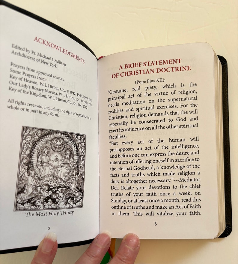 May include: Open book with black cover, displaying text and illustrations. The left page features an illustration of the Holy Trinity and the text "ACKNOWLEDGMENTS". The right page contains the text "A BRIEF STATEMENT OF CHRISTIAN DOCTRINE".