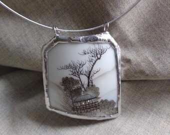 Può includere: Una collana d'argento con un ciondolo rettangolare che presenta un'illustrazione in bianco e nero di una casa giapponese con alberi e una recinzione. Il ciondolo è incorniciato da un bordo argentato.