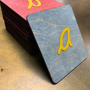 May include: Two wooden alphabet blocks with the letters "a" and "b" painted in yellow. The "a" block is blue and the "b" block is red.