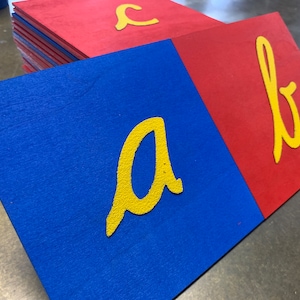 May include: Two blue and red foam squares with the letters 'a' and 'b' printed in yellow on them.