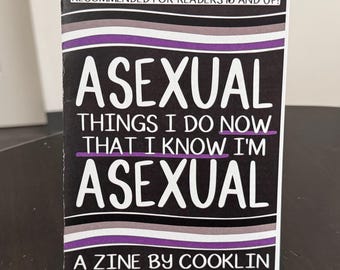 May include: A black and white zine titled "ASEXUAL THINGS I DO NOW THAT I KNOW I'M ASEXUAL" with purple and gray stripes. The zine is on a black stand and is recommended for readers 16 and up. The author is Cooklin.