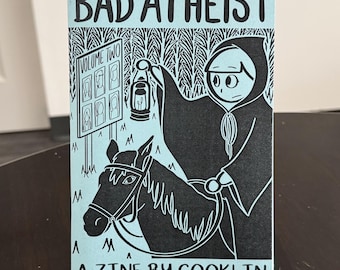 May include: A zine titled "BAD ATHEIST" with a light blue background and black illustrations. The cover art features a figure on horseback holding a lantern, with the text "A ZINE BY COOKLIN" at the bottom.