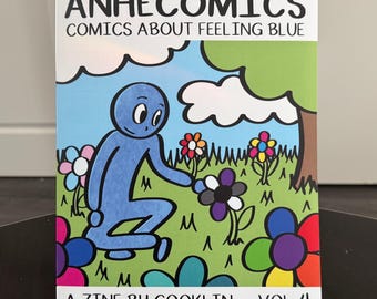 May include: A comic book titled "ANHECOMICS COMICS ABOUT FEELING BLUE" features a blue character in a garden with colorful flowers. The cover art is a cartoon illustration with the text "A ZINE BY COOKLIN • VOL. 4".