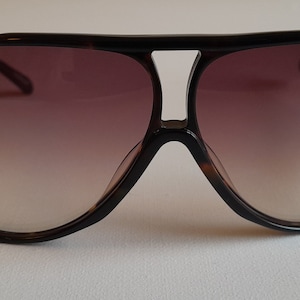 May include: Tortoiseshell aviator sunglasses with brown gradient lenses.