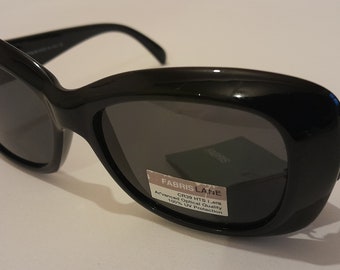 Puede incluir: Gafas de sol negras con una montura redondeada de gran tamaño. Las gafas tienen una etiqueta que dice "Fabris Lane CR39 HTL Lens Advanced Optical Quality 100% UV Protection."