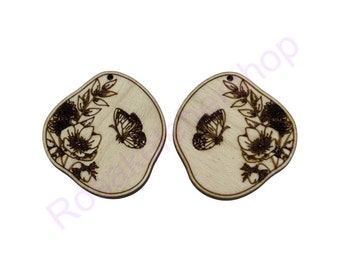 May include: Two wooden earrings with a floral and butterfly design. The earrings are light brown and have a natural wood finish.