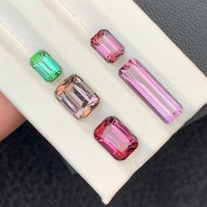 Pu&ograve; includere: Quattro pietre preziose esposte su una superficie bianca. Le pietre preziose sono tagliate in forma rettangolare. Le pietre preziose sono verdi, rosa e marroni.