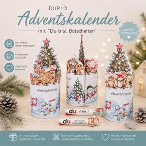 May include: Advent calendar with the text "Du bist Botschaften". The calendar features three cylindrical containers with pop-up Christmas tree designs, snowmen, and festive characters. The image also includes two candy bars with text and illustrations.