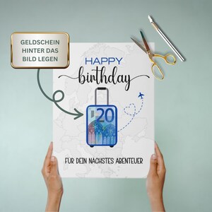 May include: A white card with the text "Happy birthday" and a blue suitcase with a 20 euro bill inside. The suitcase is on a map of the world. The text "For your next adventure" is below the suitcase. The text "Geldchein hinter das Bild legen" is in a gold box at the top of the card.