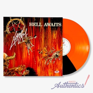 May include: A vinyl record with an orange and black color scheme. The album cover features the text "HELL AWAITS" and a graphic illustration of demons and figures in a fiery setting. The band's logo and signature are also visible.