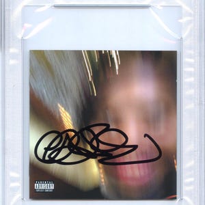 May include: A CD cover featuring a blurred image with a black autograph. The cover is encased in a protective plastic holder with a PSA/DNA certification label. The Parental Advisory Explicit Content warning is visible.