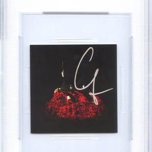 May include: A CD insert featuring a black background with a red floral design and a white signature. The insert is encased in a clear protective holder with a blue and white label at the top that reads "CD INSERT CONAN GRAY PSA/DNA CERTIFIED AUTHENTIC AUTO".
