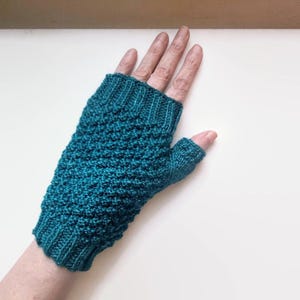 May include: Teal blue fingerless knitted gloves with a textured pattern.