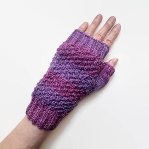 May include: Purple and pink fingerless gloves with a textured knit pattern.