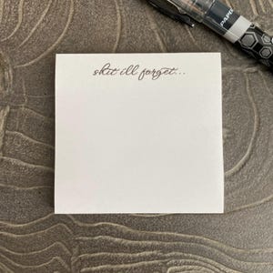 May include: A white sticky note with the text "shit i'll forget..." written in brown ink.