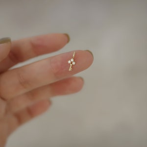 May include: A gold key charm with clear cubic zirconia stones. The charm is small and delicate, perfect for adding a touch of sparkle to a necklace or bracelet.