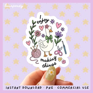 May include: A sticker featuring a white goose with a green bow, surrounded by flowers, hearts, and crafting tools. The text "I enjoy making things" is included. The background is a light purple with yellow stars.