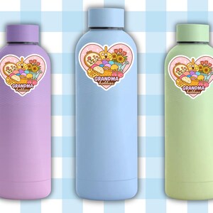 May include: Three insulated water bottles in pastel colors: lavender, light blue, and green. Each bottle has a heart-shaped sticker with the text "Grandma Hobbies" and a graphic of craft supplies. The bottles have matching colored lids.