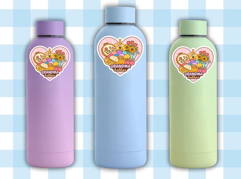 May include: Three insulated water bottles in pastel colors: lavender, light blue, and green. Each bottle has a heart-shaped sticker with the text "Grandma Hobbies" and a graphic of craft supplies. The bottles have matching colored lids.