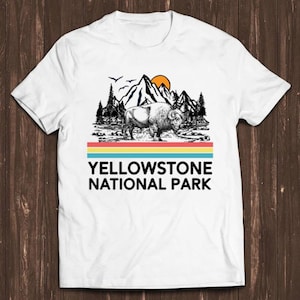 Peut inclure: T-shirt blanc avec un graphique de style vintage d'un bison dans le parc national de Yellowstone. Le graphique présente une chaîne de montagnes, un coucher de soleil et une bande arc-en-ciel.